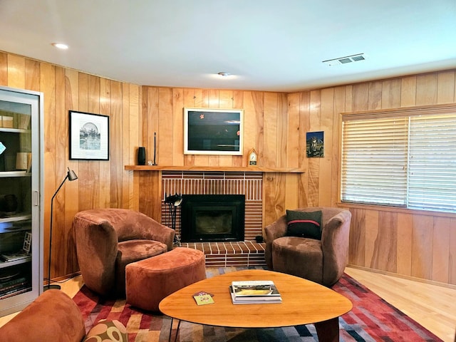 living room with wood-type flooring, a fireplace, and wood walls