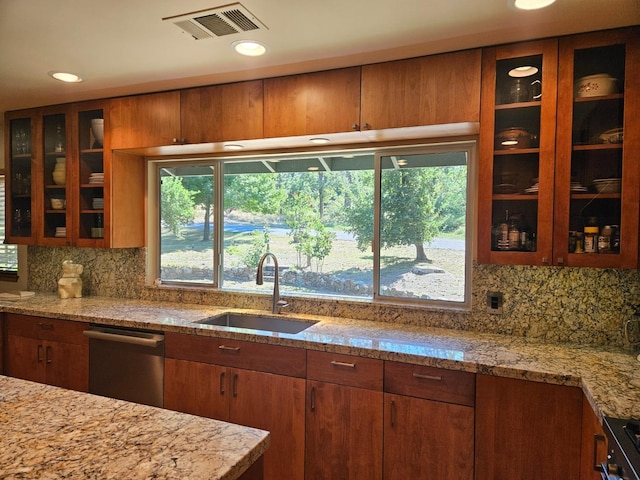 kitchen featuring sink, dishwasher, range, backsplash, and light stone counters