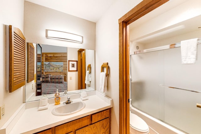 full bathroom featuring enclosed tub / shower combo, vanity, and toilet