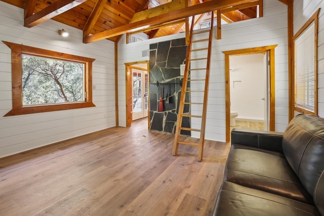 unfurnished living room featuring wooden walls, wood ceiling, a fireplace, hardwood / wood-style flooring, and lofted ceiling with beams