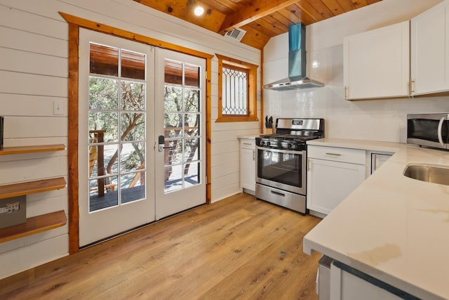 kitchen featuring light hardwood / wood-style flooring, white cabinets, appliances with stainless steel finishes, wall chimney exhaust hood, and wooden ceiling