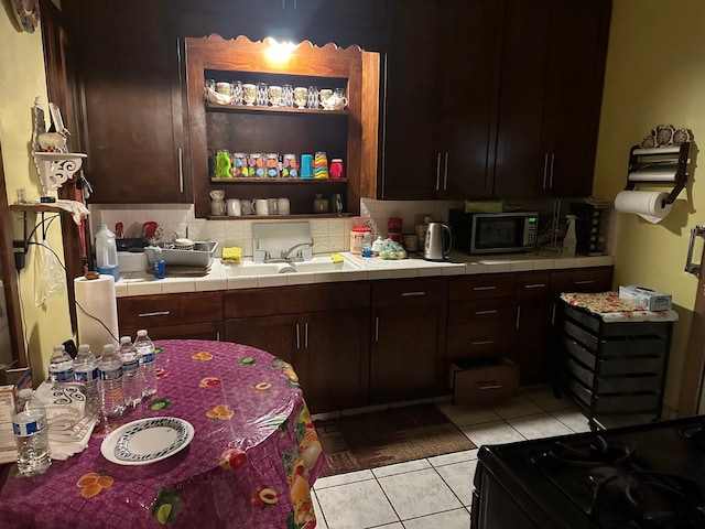 kitchen featuring light tile flooring, dark brown cabinets, backsplash, tile countertops, and sink