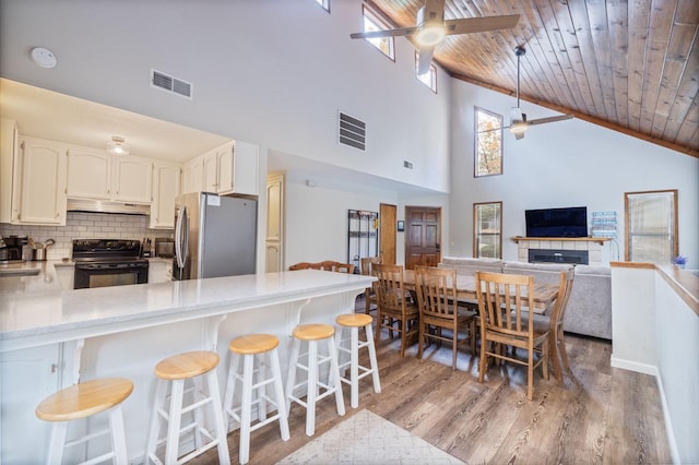 kitchen with wood ceiling, stainless steel refrigerator, kitchen peninsula, black range with electric cooktop, and ceiling fan