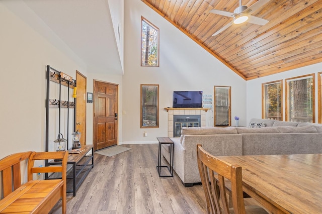 living room with wood-type flooring, high vaulted ceiling, wooden ceiling, ceiling fan, and a tiled fireplace