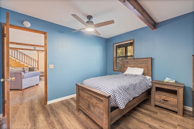 bedroom featuring ceiling fan, wood-type flooring, and beam ceiling