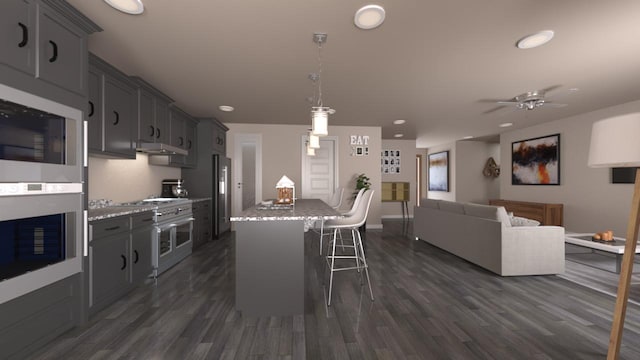 kitchen featuring a breakfast bar area, gray cabinetry, ceiling fan, and light stone countertops