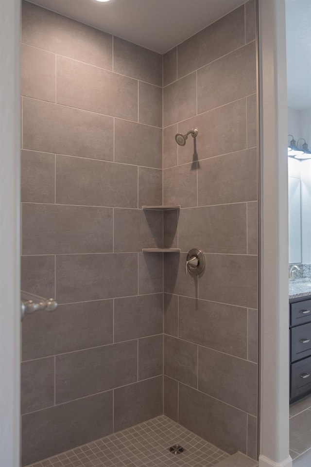 bathroom featuring tiled shower and vanity