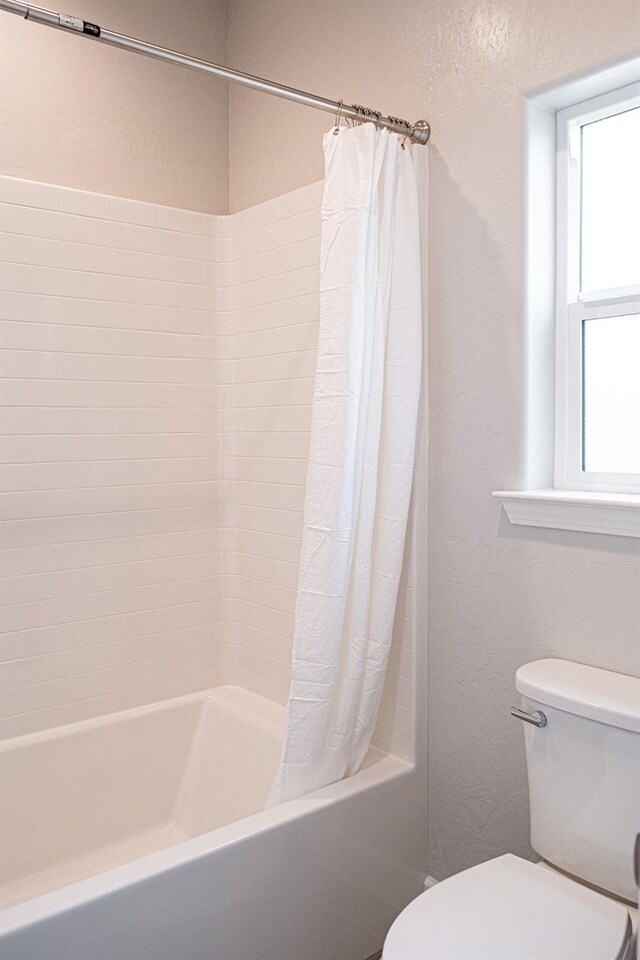 bathroom with toilet and shower / bathtub combination with curtain