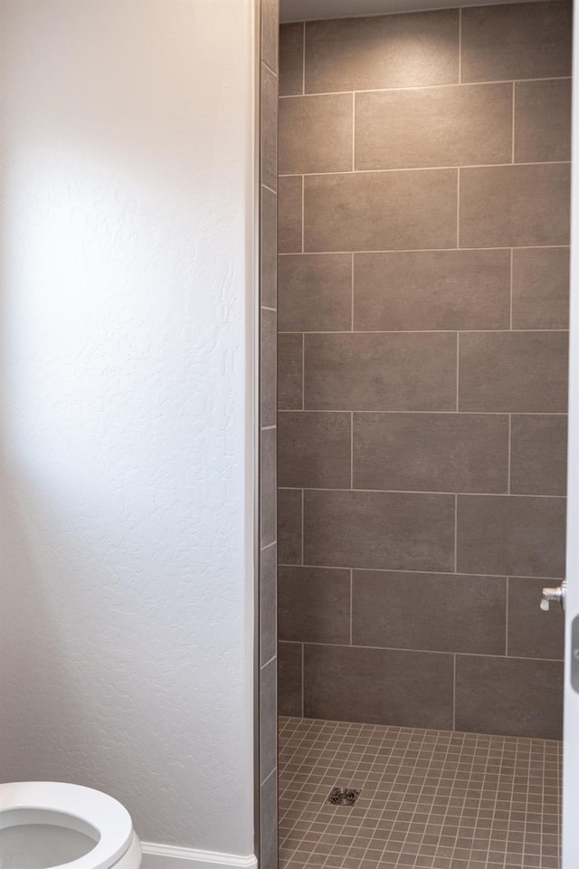 bathroom with toilet and tiled shower