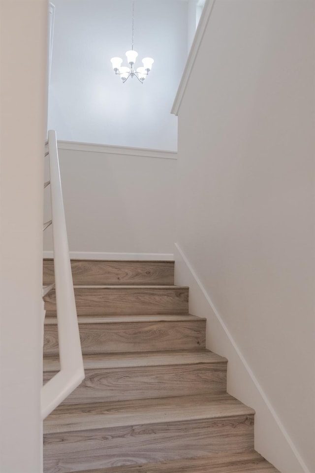 stairs featuring a towering ceiling, light hardwood / wood-style floors, and a chandelier