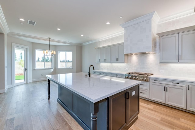 kitchen featuring stainless steel gas cooktop, visible vents, decorative backsplash, ornamental molding, and a sink