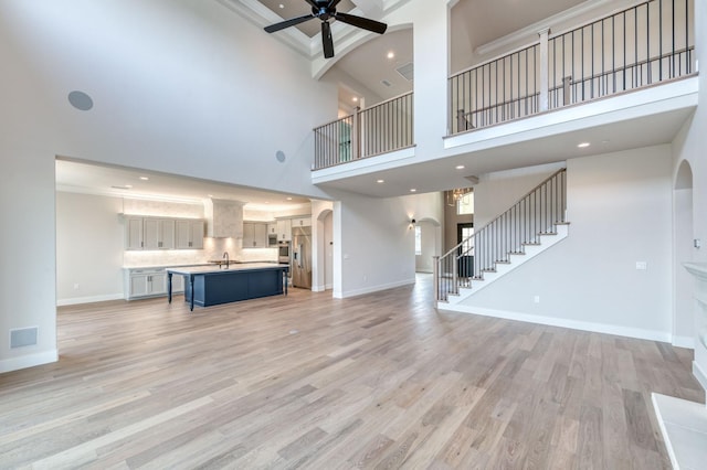 unfurnished living room with stairs, baseboards, visible vents, and light wood-style floors