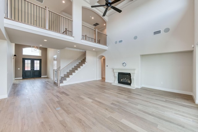 unfurnished living room with a glass covered fireplace, wood finished floors, visible vents, and baseboards