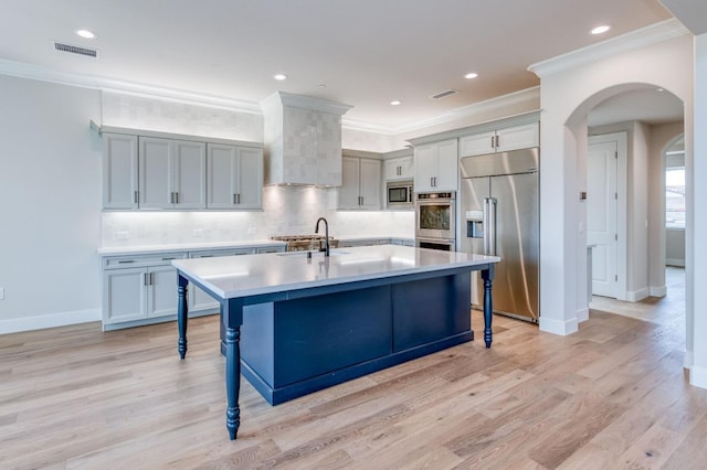 kitchen with built in appliances, light countertops, a sink, and a kitchen breakfast bar