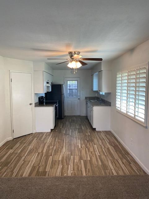 kitchen featuring ceiling fan, white cabinetry, dark colored carpet, range, and sink