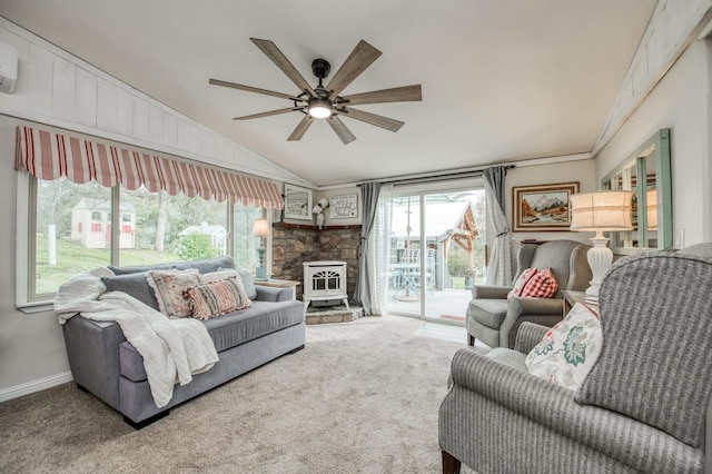 carpeted living room featuring vaulted ceiling, a wood stove, a wealth of natural light, and ceiling fan