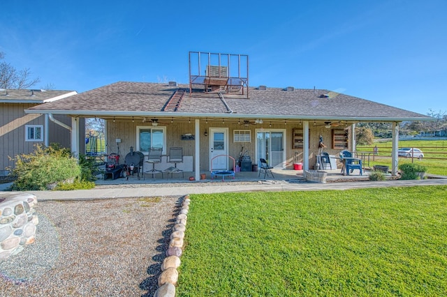 rear view of house featuring a patio, a ceiling fan, fence, a yard, and a shingled roof