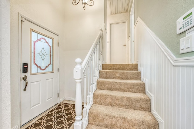 entryway with stairs, a decorative wall, and wainscoting