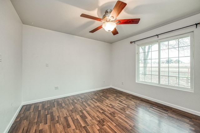 empty room featuring a ceiling fan, dark wood-style flooring, and baseboards
