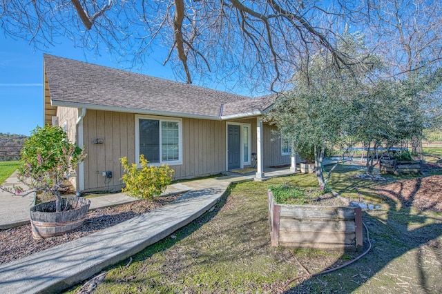 view of front of property featuring a shingled roof and a vegetable garden