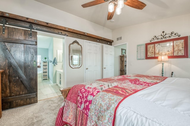 carpeted bedroom with visible vents, ceiling fan, vaulted ceiling, a barn door, and connected bathroom