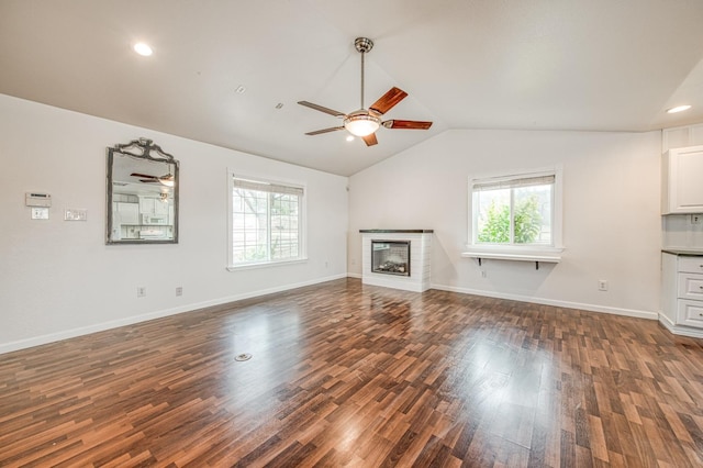 unfurnished living room featuring a wealth of natural light, lofted ceiling, ceiling fan, and wood finished floors