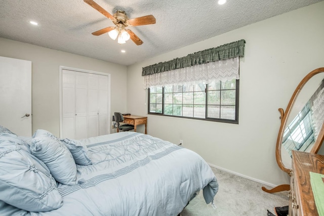 carpeted bedroom with a closet, baseboards, a textured ceiling, and a ceiling fan