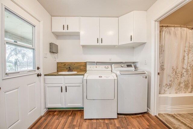 clothes washing area featuring washing machine and clothes dryer, cabinet space, dark wood-type flooring, and a sink