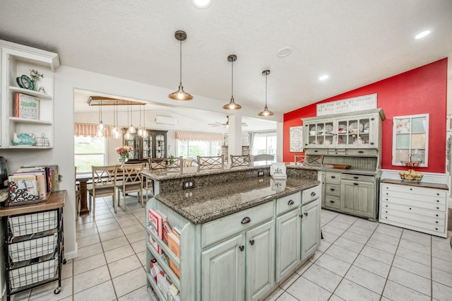 kitchen with a wealth of natural light, open shelves, a center island, light tile patterned floors, and lofted ceiling