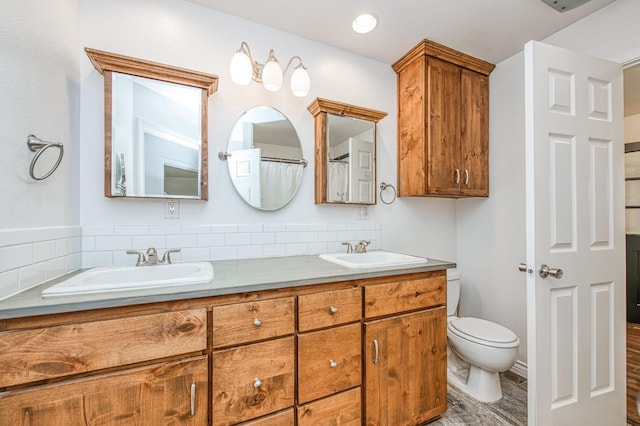 full bathroom with double vanity, toilet, and a sink