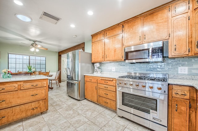kitchen featuring visible vents, ceiling fan, light countertops, brown cabinets, and stainless steel appliances