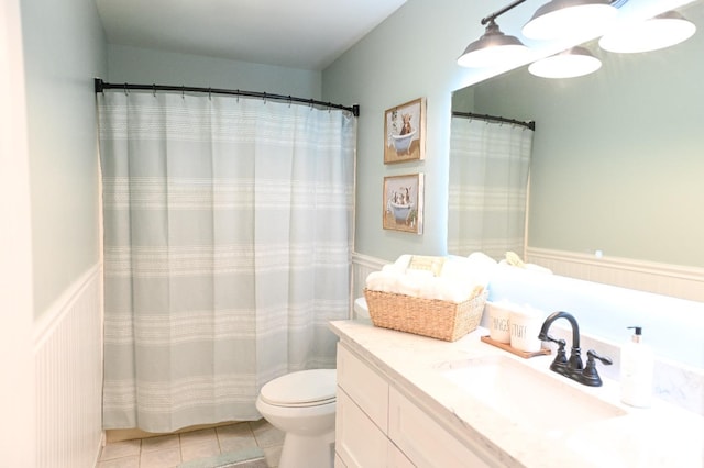 full bathroom with tile patterned floors, wainscoting, toilet, and vanity