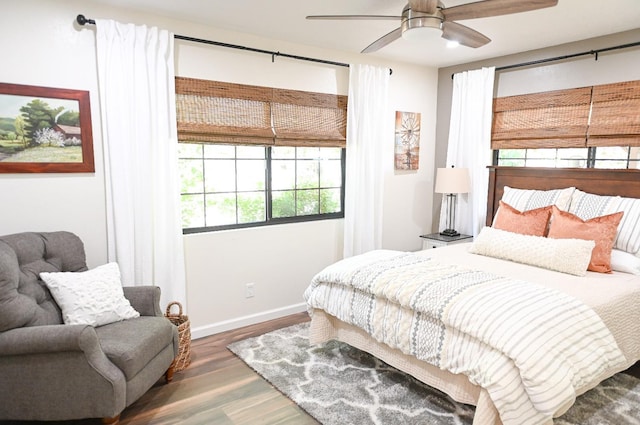 bedroom featuring multiple windows, a ceiling fan, baseboards, and wood finished floors