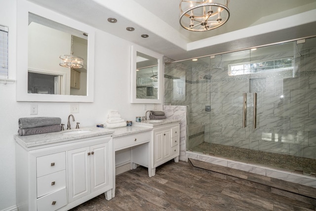 bathroom with hardwood / wood-style flooring, a notable chandelier, walk in shower, and vanity