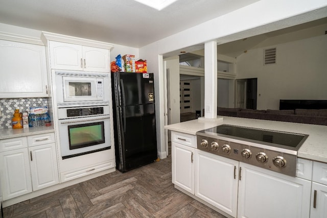 kitchen featuring black fridge, white microwave, white cabinetry, oven, and stainless steel gas stovetop