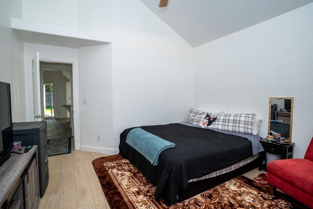 bedroom with ceiling fan, high vaulted ceiling, and light wood-type flooring