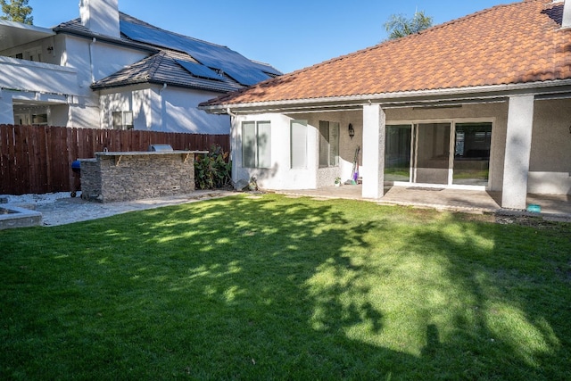 rear view of property with a bar, a yard, a patio, and exterior kitchen