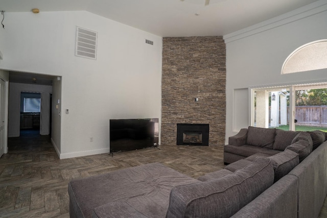 living room with a stone fireplace, dark parquet flooring, and a towering ceiling