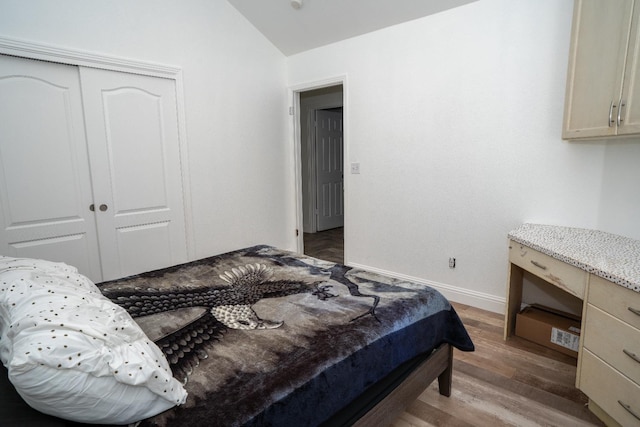 bedroom with lofted ceiling, a closet, and dark hardwood / wood-style floors