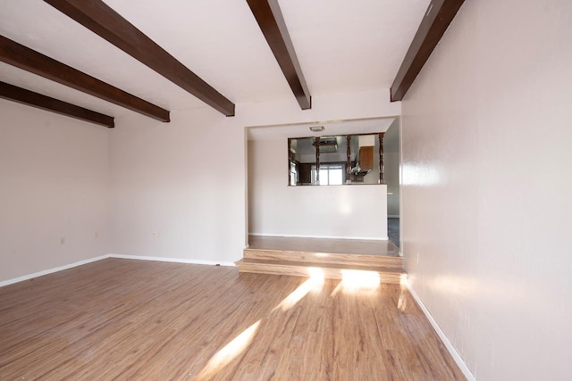 empty room with beam ceiling and light hardwood / wood-style flooring