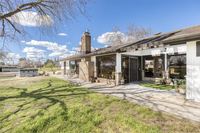 back of house featuring a yard, a hot tub, and a patio