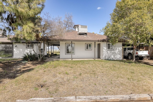 back of property featuring a lawn and a carport