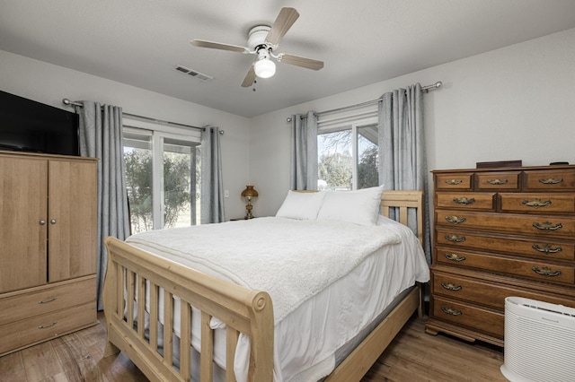 bedroom with multiple windows, wood-type flooring, and ceiling fan