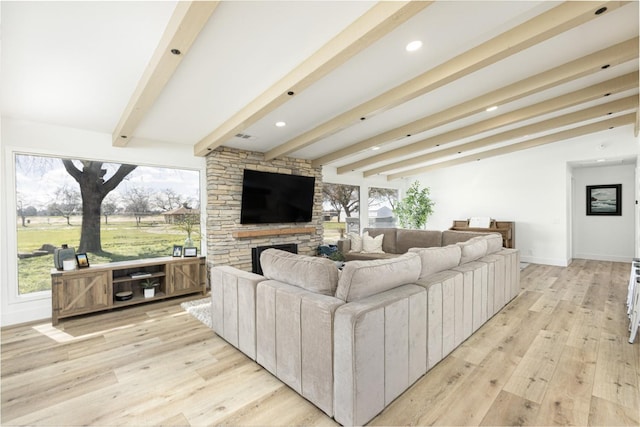 living room with beamed ceiling, a fireplace, and light hardwood / wood-style floors