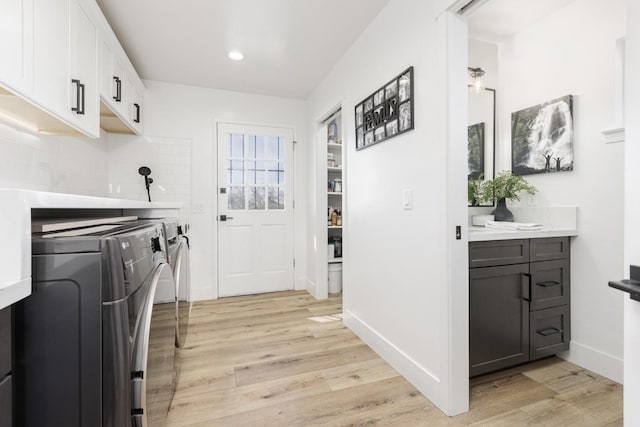 washroom featuring cabinets, light wood-type flooring, and independent washer and dryer