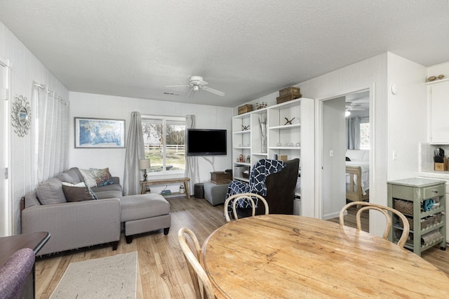 dining space with ceiling fan, light hardwood / wood-style floors, and a textured ceiling