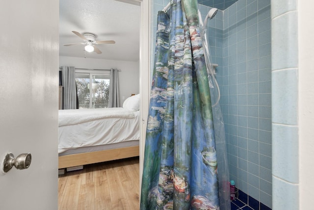 bedroom with ceiling fan, wood-type flooring, and a textured ceiling