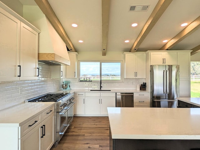 kitchen featuring appliances with stainless steel finishes, beamed ceiling, white cabinetry, sink, and light hardwood / wood-style floors