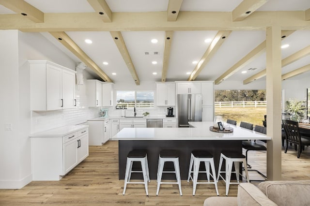 kitchen featuring stainless steel appliances, white cabinetry, a breakfast bar, and a spacious island