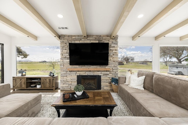 living room with beamed ceiling, a healthy amount of sunlight, and a fireplace